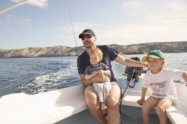 Mature man steering motor boat with sons, Lopar, Rab Island, Croatia - ISF10101
