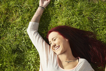 Blick von oben auf eine junge Frau, die lachend im Gras liegt - ISF10143