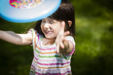 Young girl throwing frisbee in garden - ISF10176