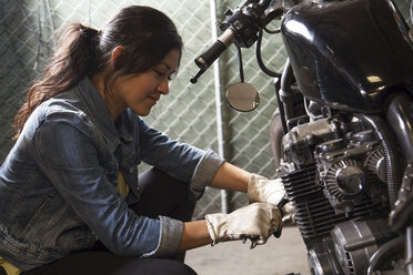 Mechanikerin bei der Arbeit an einem Motorrad in der Werkstatt - ISF10202