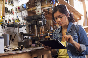 Mechanikerin mit digitalem Tablet in der Werkstatt - ISF10204