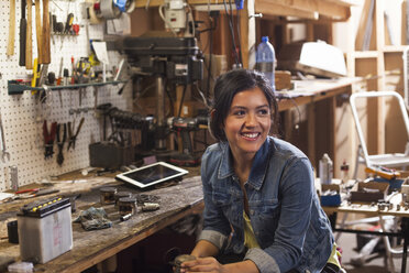 Porträt eines weiblichen Mechanikers in einer Werkstatt, lächelnd und den Blick abwendend - ISF10205