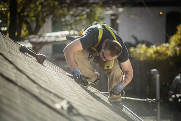 Arbeiter bei der Installation von Solarmodulen auf dem Dach eines Hauses - ISF10225