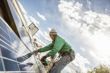 Ein Bautruppmitglied bei der Installation eines Solarpanels auf einem Haus - ISF10228