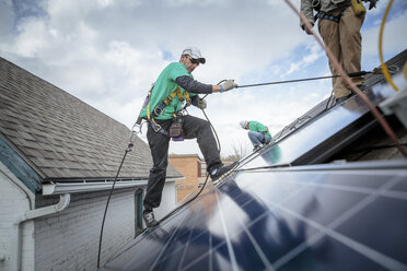 Bautrupp bei der Installation von Sonnenkollektoren auf einem Haus - ISF10229