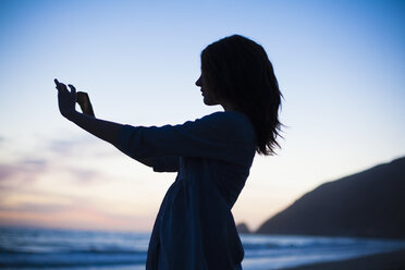 Frau macht Selfie am Strand bei Sonnenuntergang, Malibu, Kalifornien, USA - ISF10283