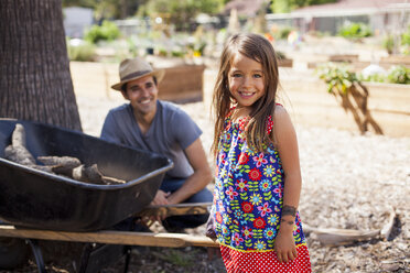 Portrait of girl in community garden with father and wheelbarrow - ISF10293