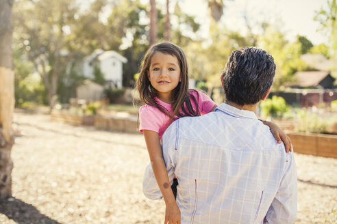 Porträt eines Mädchens im Gemeinschaftsgarten, das von seinem Vater getragen wird - ISF10324