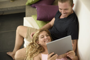 Couple reclining on sofa browsing digital tablet - ISF10350