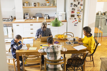 Großeltern am Esstisch mit Enkelkindern bei den Hausaufgaben - CAIF20693