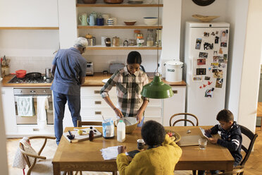 Grandparents and grandchildren baking and using digital tablet in kitchen - CAIF20697