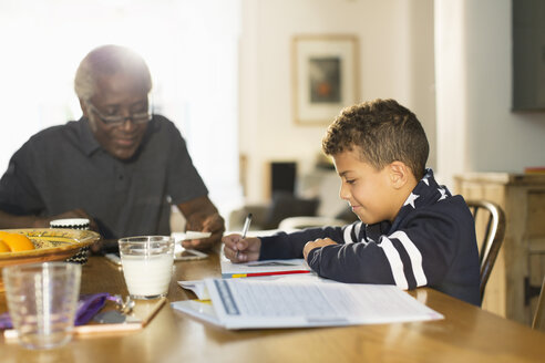 Großvater am Tisch mit Enkel bei den Hausaufgaben - CAIF20703