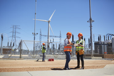 Engineers using digital tablet at sunny wind turbine power plant - CAIF20758