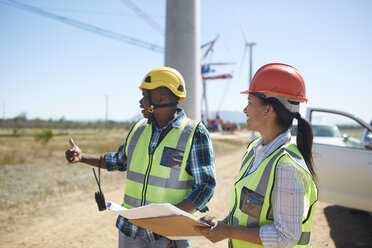 Engineers with blueprints talking at sunny power plant - CAIF20759