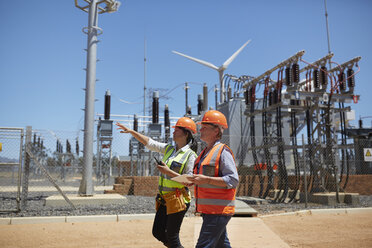 Female engineers with digital tablet at sunny power plant - CAIF20766