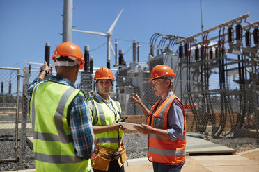 Engineers with digital tablet at sunny power plant - CAIF20771