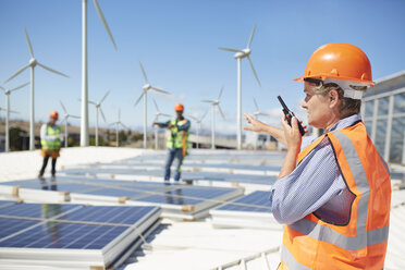 Female engineer using walkie-talkie at alternative energy power plant - CAIF20778