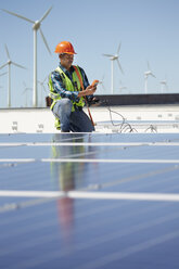 Ingenieur mit Ausrüstung bei der Inspektion von Solarmodulen in einem sonnigen Kraftwerk - CAIF20780