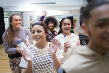 Lächelnde, begeisterte Teenager-Mädchen trinken Wasser und jubeln im Tanzkurs im Studio - CAIF20813