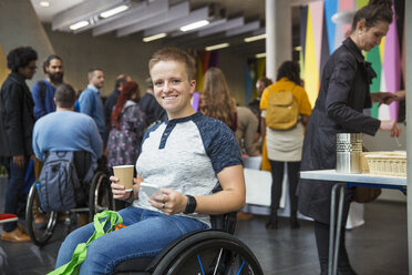 Porträt einer lächelnden, selbstbewussten Frau im Rollstuhl, die auf einer Konferenz ein Smartphone benutzt - CAIF20922
