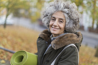 Porträt lächelnde, selbstbewusste aktive ältere Frau mit Yogamatte - CAIF20931