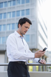 Businessman using cell phone in the city - DIGF04653