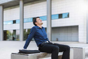 Businessman sitting outdoors leaning back - DIGF04663