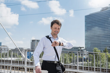 Geschäftsmann auf einer Brücke, der die Zeit überprüft - DIGF04685