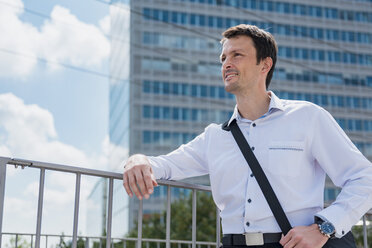 Smiling businessman in the city looking around - DIGF04688