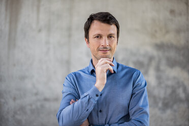 Portrait of confident businessman in front of concrete wall - DIGF04710