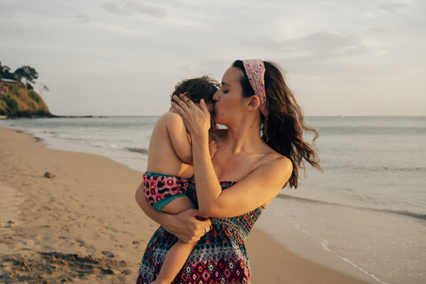 Thailand, Krabi, Koh Lanta, Mutter mit kleiner Tochter auf den Schultern am Strand bei Sonnenuntergang, lizenzfreies Stockfoto