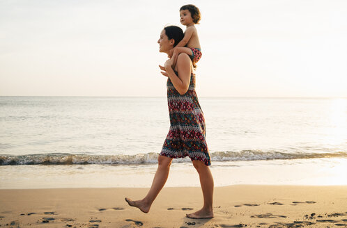 Thailand, Krabi, Koh Lanta, Mother with little daughter on her shoulders on the beach at sunset - GEMF02079