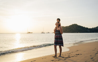 Thailand, Krabi, Koh Lanta, Mutter mit kleiner Tochter auf den Schultern am Strand bei Sonnenuntergang - GEMF02080