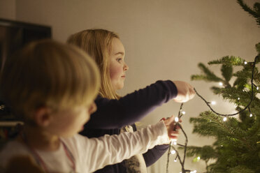 Junge Brüder und Schwestern beim Aufstellen der Weihnachtsbeleuchtung - CUF32436