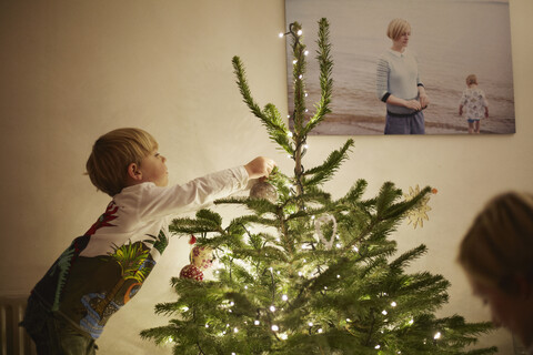 Junge bringt Lichter am Weihnachtsbaum an, lizenzfreies Stockfoto