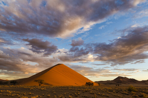 Sonnenaufgang auf einer Sanddüne mit Wolken darüber, Soussvlei, Namibia - CUF32538