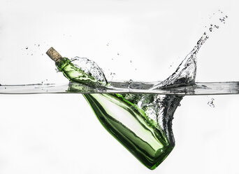 Oberflächenansicht einer grünen Flasche, die in klares Wasser spritzt - CUF32556