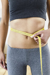 Cropped view of young woman measuring her waist with tape measure - CUF32609