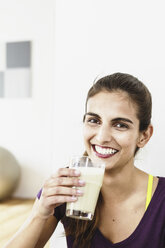 Portrait of young woman taking an exercise break drinking juice - CUF32618