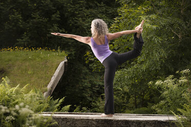 Ältere Frau übt Yoga-Tänzerin-Pose im Garten - CUF32624