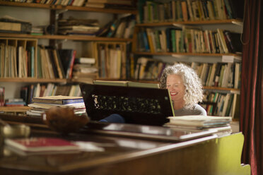 Ältere Frau lächelt beim Klavierspielen im Wohnzimmer - CUF32635