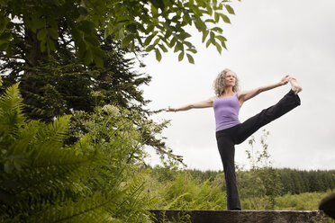 Mature woman practicing yoga pose on footbridge - CUF32656