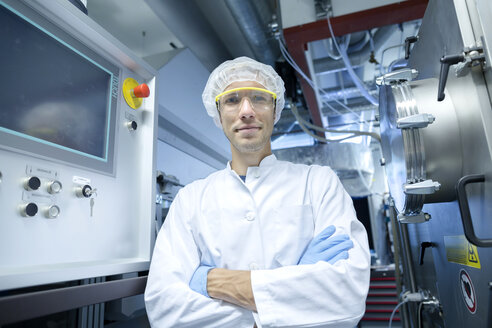 Porträt eines männlichen Wissenschaftlers mit verschränkten Armen in einem Laborreinraum - CUF32680