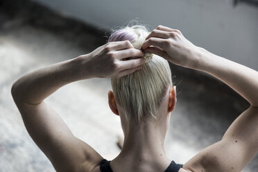 Frau bindet Haare im Studio hoch - CUF32690