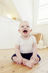 Porträt eines lächelnden kleinen Jungen auf dem Boden sitzend - CUF32793