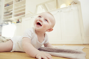 Smiling baby boy crawling on sitting room floor - CUF32795
