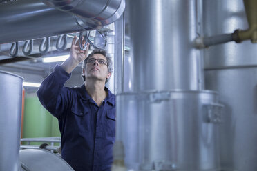 Engineer inspecting pipes in power station - CUF32799