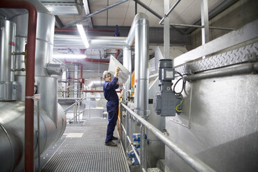 Engineer removing cover from equipment in power station - CUF32800