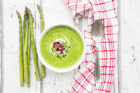 Green asparagus soup with pomegranate seeds and black sesame stock photo