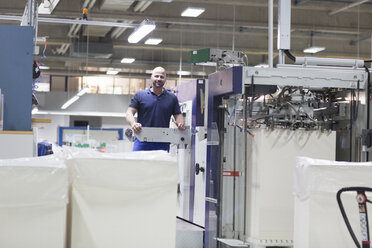 Arbeiter an einer Maschine in einer Papierverpackungsfabrik - CUF32893